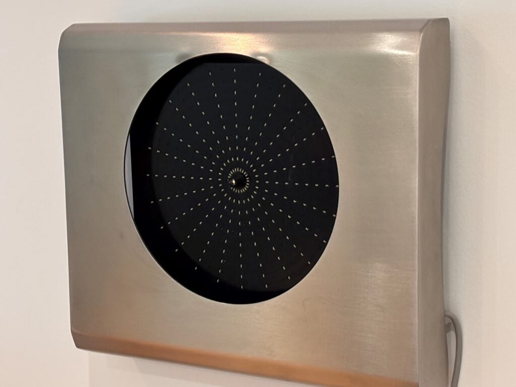 Close-up of a brushed stainless steel panel with a circular black perforated dial.