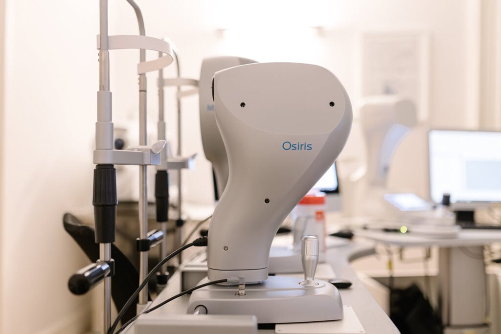White Osiris robotic arm on a lab bench with monitors and equipment in the background.